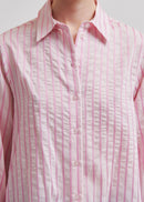 Woman wearing a pink  shirt with blue jeans on a light grey background