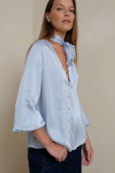 Woman wearing a light blue blouse with a beige background