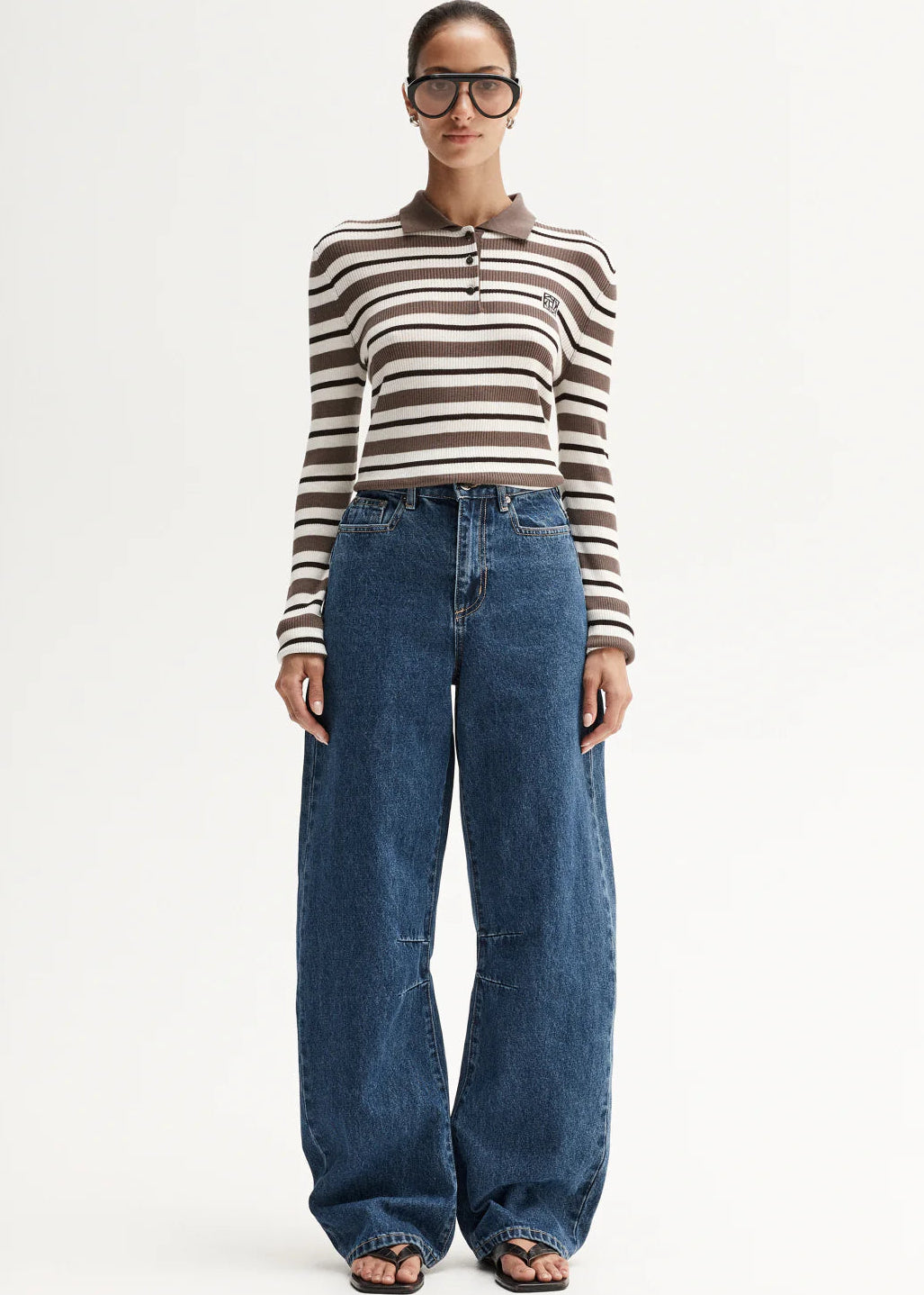 Person wearing a striped shirt and blue jeans on a white background