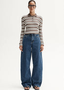 Person wearing a striped shirt and blue jeans on a white background