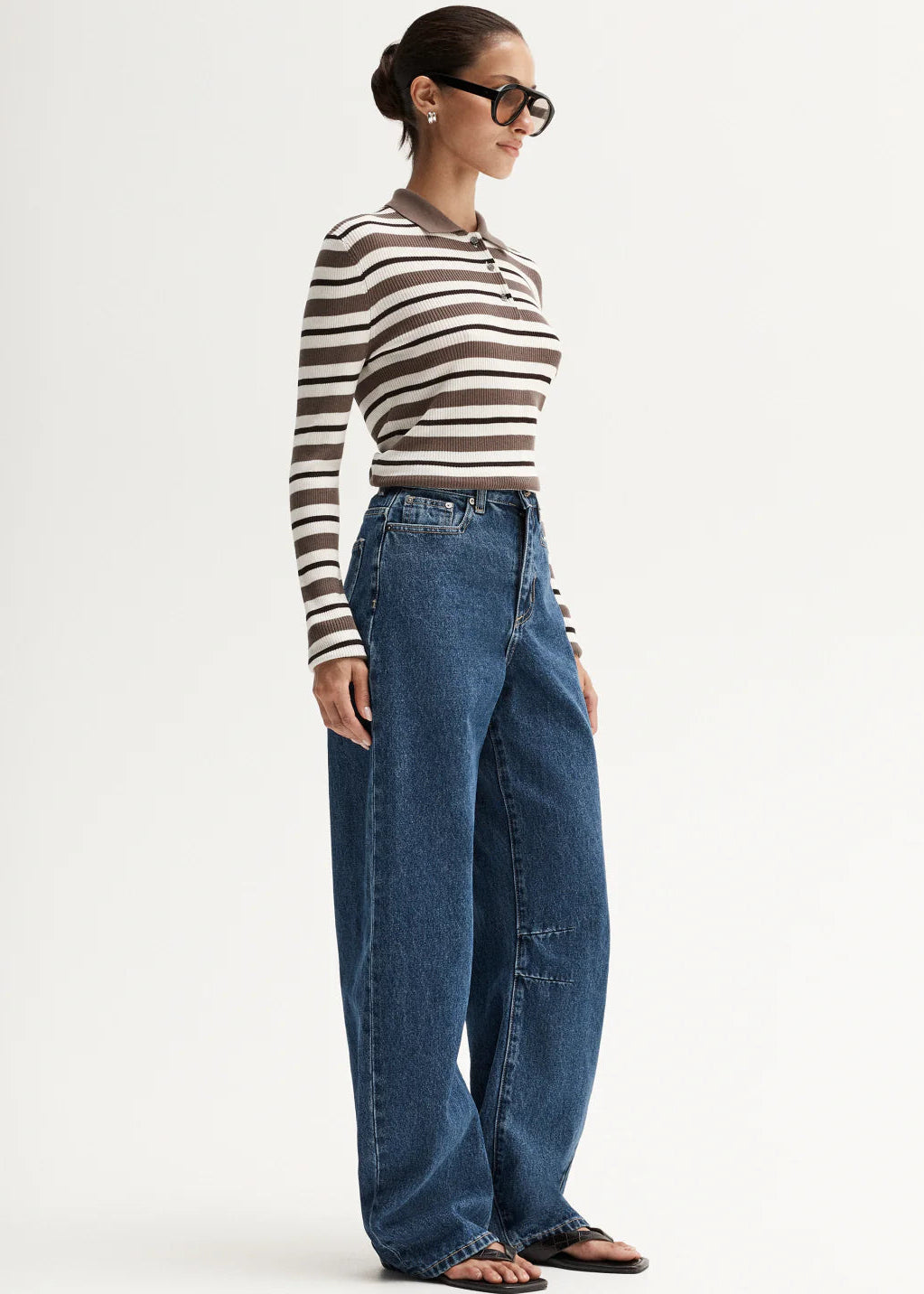 Person wearing a striped shirt and blue jeans on a white background