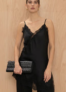 Woman wearing a black lace outfit holding a matching clutch against a wooden background