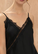 Black lace-trimmed slip dress worn by a model against a neutral background