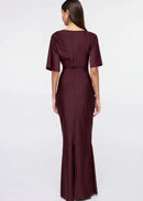 Woman wearing a burgundy evening gown with ruffled details on a white background