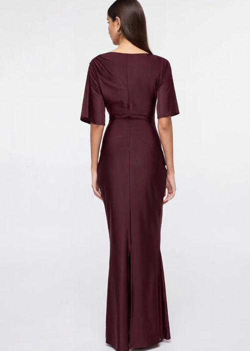 Woman wearing a burgundy evening gown with ruffled details on a white background