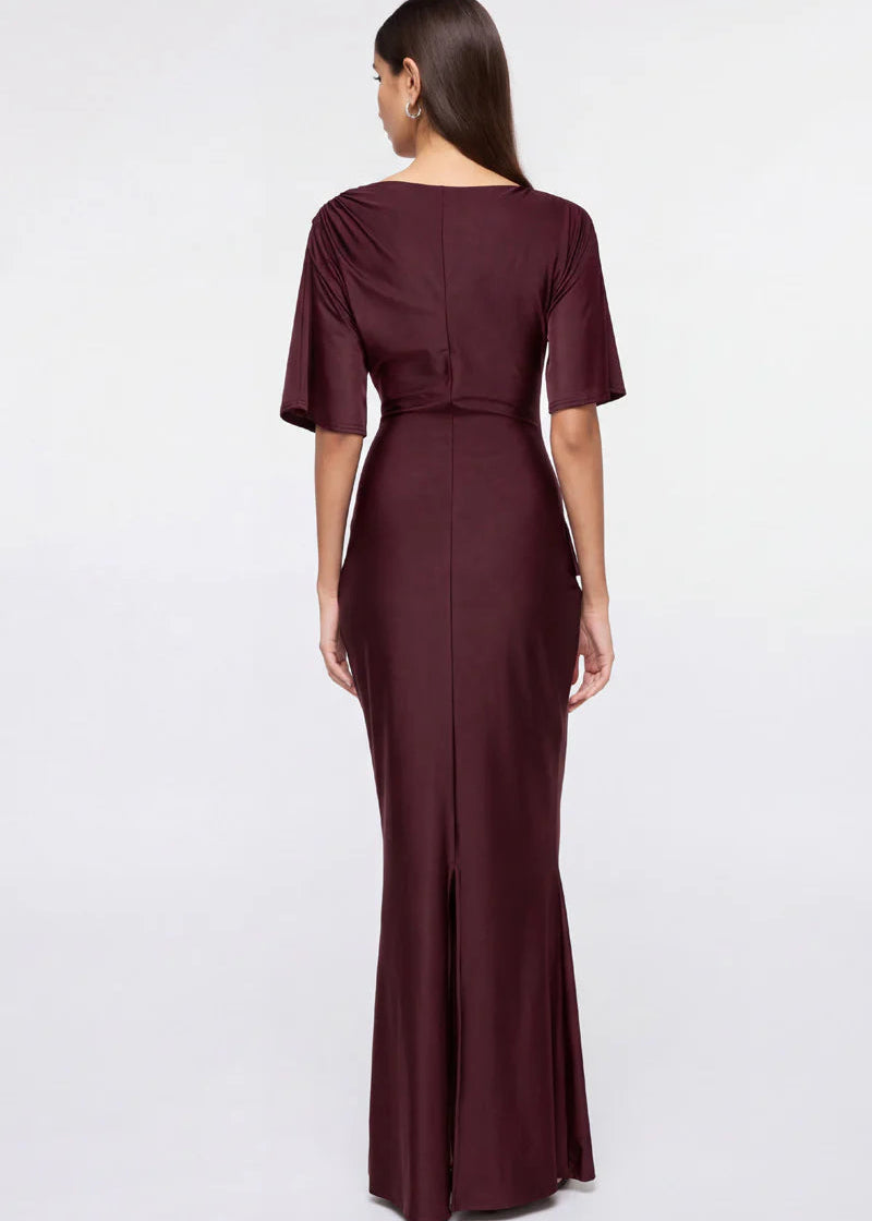 Woman wearing a burgundy evening gown with ruffled details on a white background