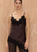 Woman wearing a black lace-trimmed top and pants against a wooden background