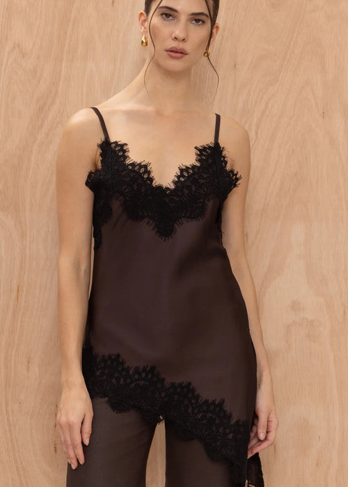 Woman wearing a black lace lingerie set against a wooden background