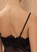 Black lace-trimmed top worn by a person against a neutral background