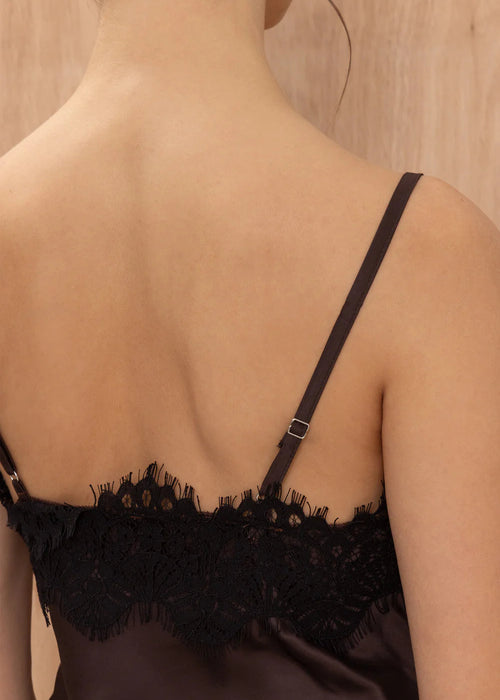 Black lace-trimmed top worn by a person against a neutral background