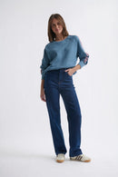 Woman wearing a blue sweater and jeans on a white background