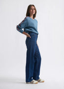 Woman wearing a blue sweater and jeans on a white background