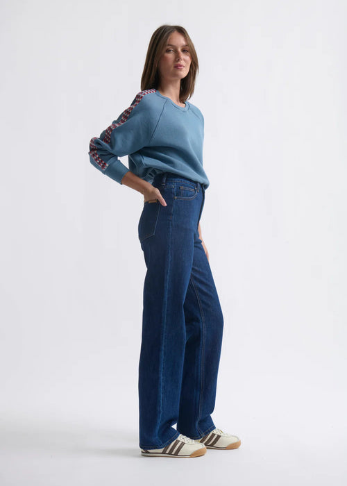 Woman wearing a blue sweater and jeans on a white background