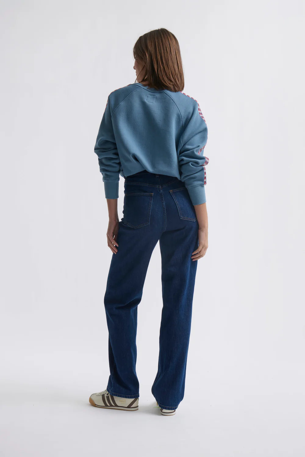 Woman wearing a blue sweater and jeans on a white background