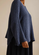 Woman wearing a blue knitted sweater on a beige background
