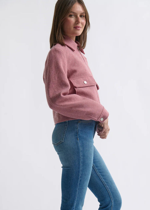 Woman wearing a pink jacket and blue jeans on a white background