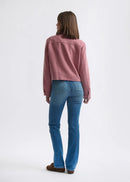 Woman wearing a pink jacket and blue jeans on a white background