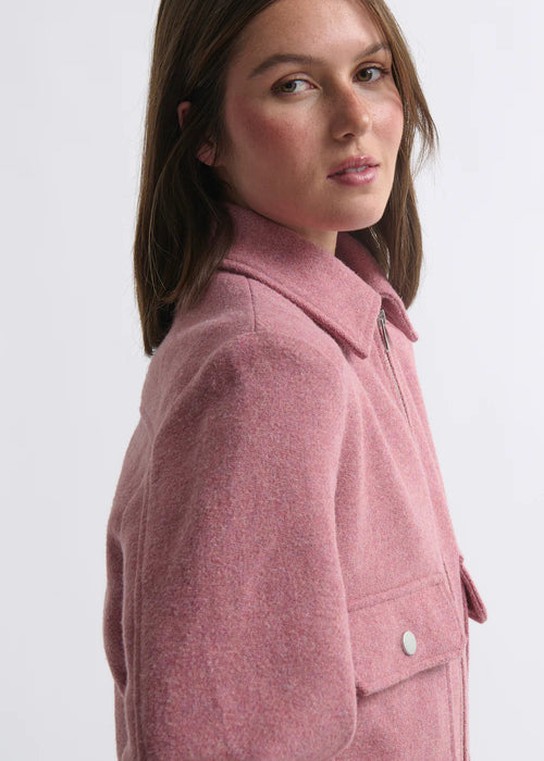 Woman wearing a pink jacket and blue jeans on a white background
