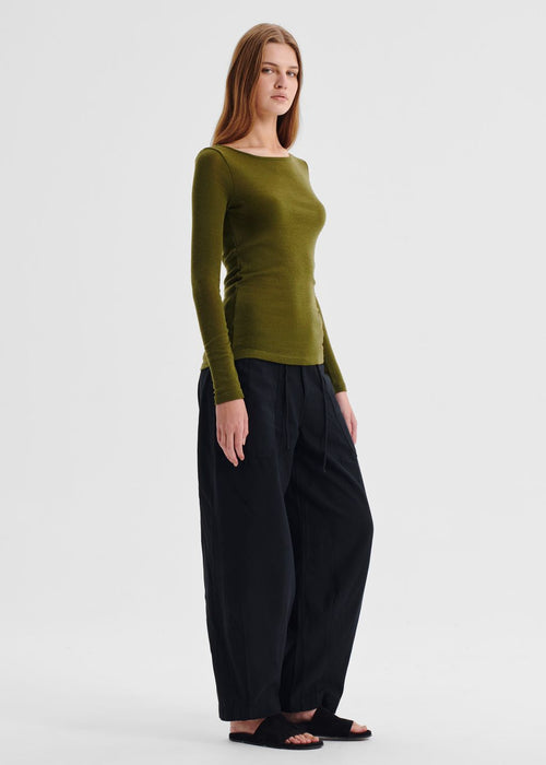 Woman wearing a green sweater and black pants on a white background
