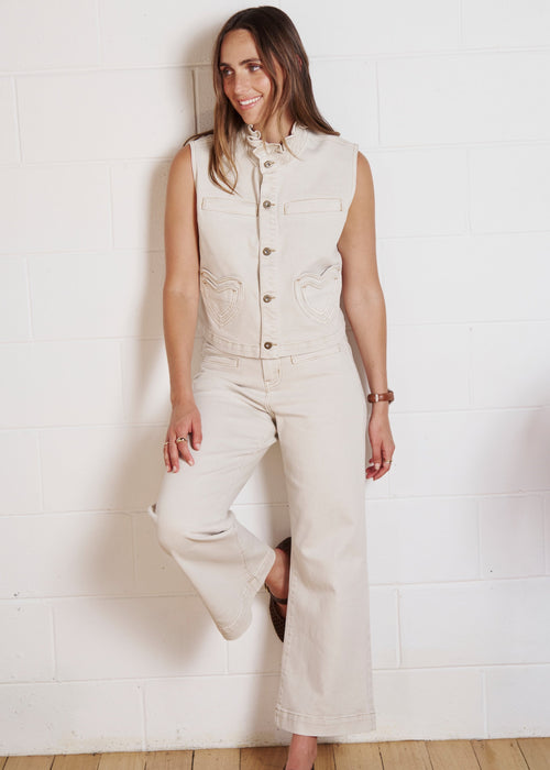 Woman wearing sand coloured jeans on white background