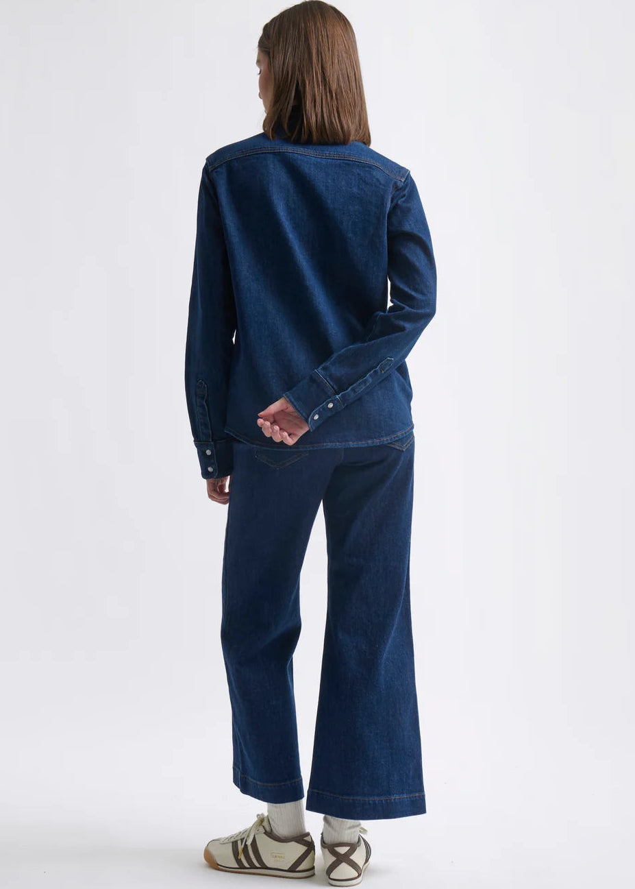 Person wearing a blue denim outfit on a white background