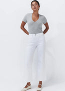 A woman modelling a light grey short-sleeve v-neck top and white cropped wide-leg jeans, paired with off-white Mary Jane flats, against a plain white studio background.