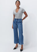 Woman wearing wide leg blue jeans on white background