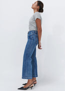 Woman wearing wide leg blue jeans on white background