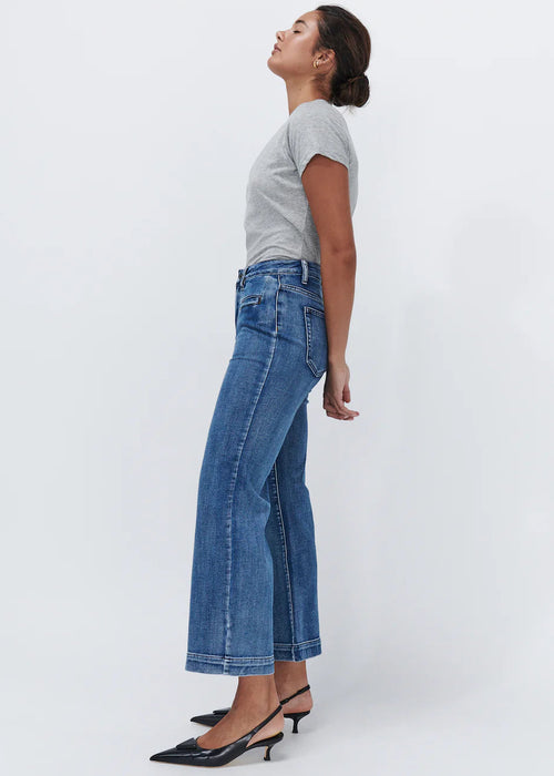 Woman wearing wide leg blue jeans on white background