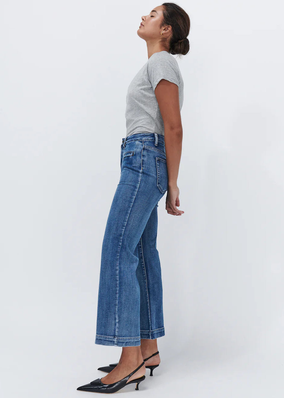 Woman wearing wide leg blue jeans on white background