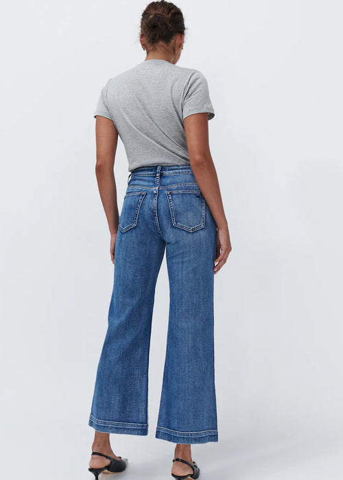Woman wearing wide leg blue jeans on white background