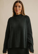 Woman wearing a dark green sweater against a beige background