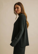 Woman wearing a dark green sweater against a beige background