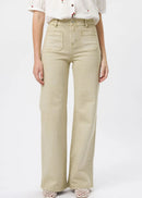 A model wearing a pair of light beige wide-leg jeans with a white embroidered short-sleeve blouse and beige crochet flat shoes, shown from the chest down on a light grey studio background.