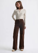 Woman wearing a white sweater and brown pants on a white background
