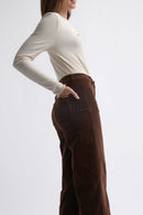Woman wearing a white sweater and brown pants on a white background