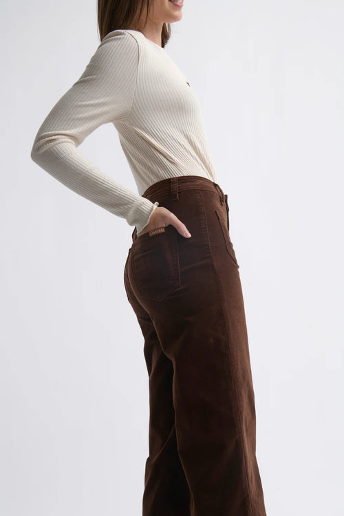 Woman wearing a white sweater and brown pants on a white background