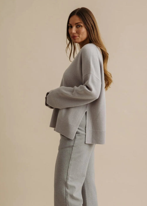 Woman wearing a light grey outfit on a beige background