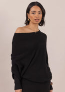 Woman wearing a black off-shoulder top and pants on a beige background