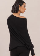 Woman wearing a black off-shoulder top and pants on a beige background