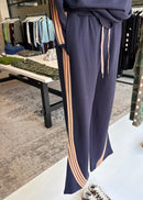 Navy pants with pink stripes on an ironing board in a store setting