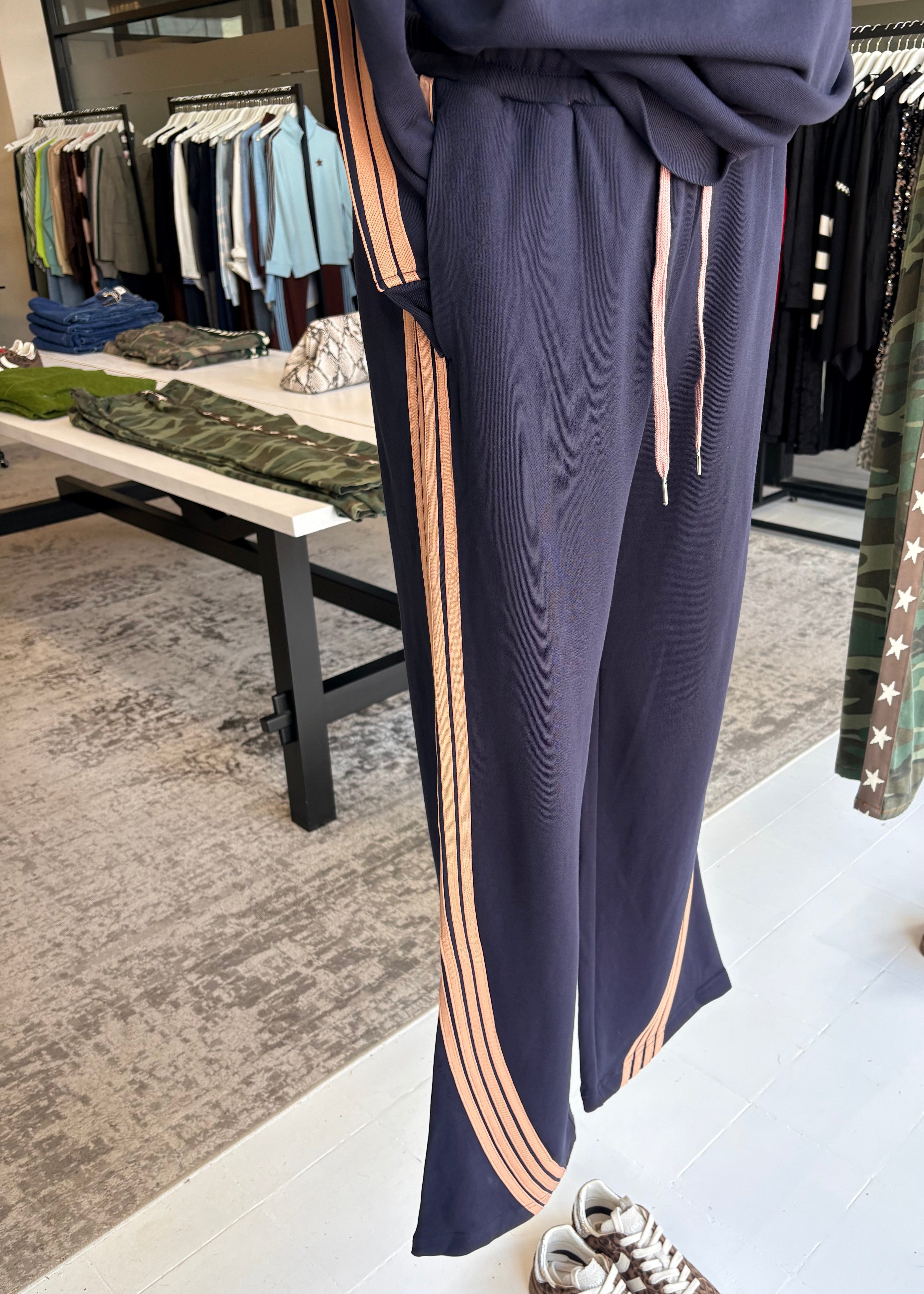 Navy pants with pink stripes on an ironing board in a store setting