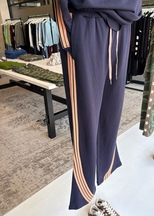 Navy pants with pink stripes on an ironing board in a store setting