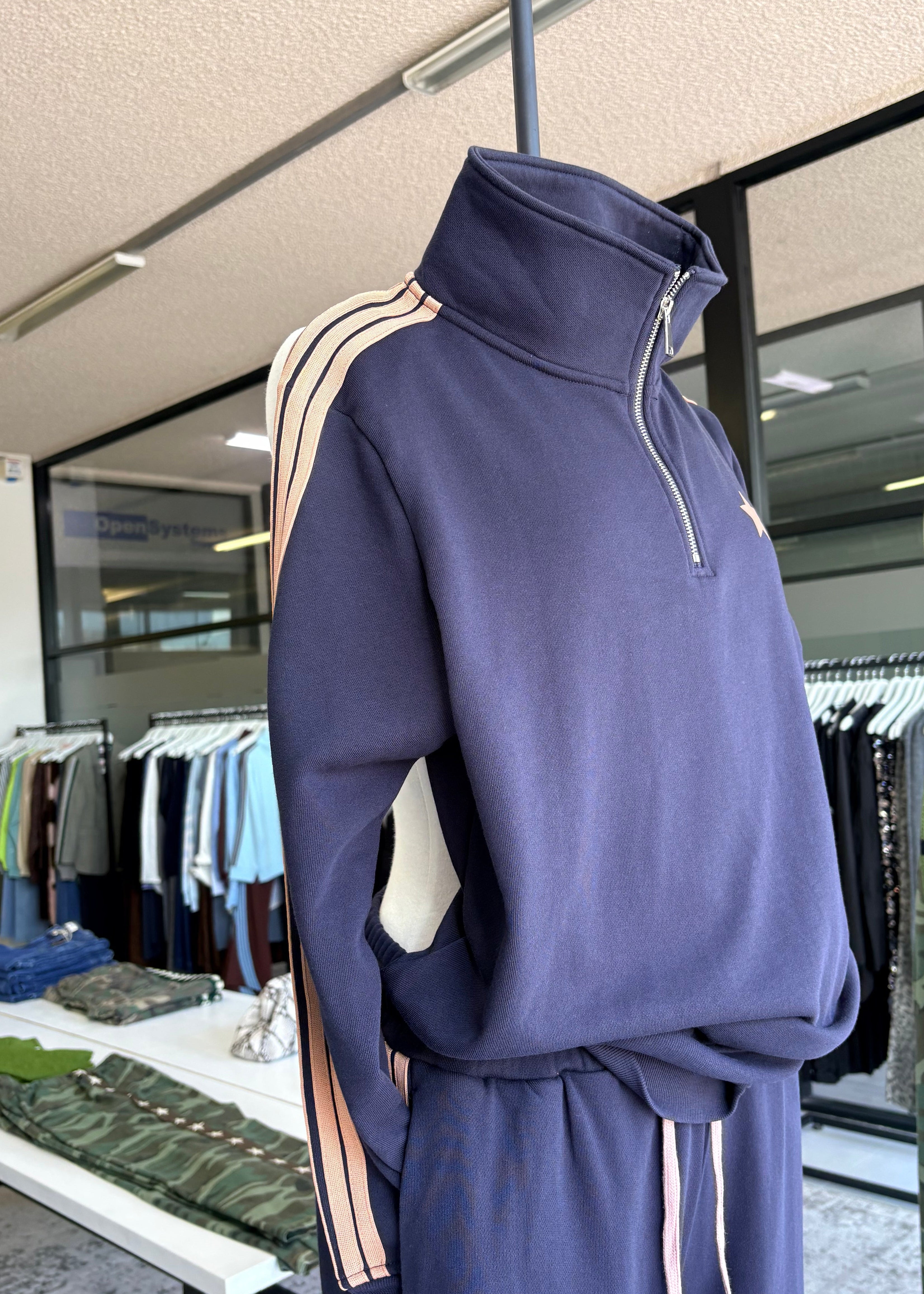 Navy tracksuit with beige accents hanging in a store