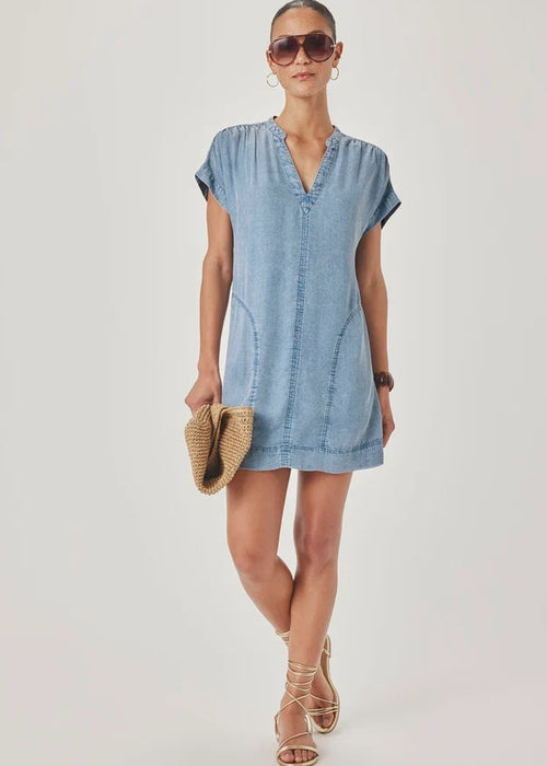 Woman wearing a blue dress holding a straw bag against a white background