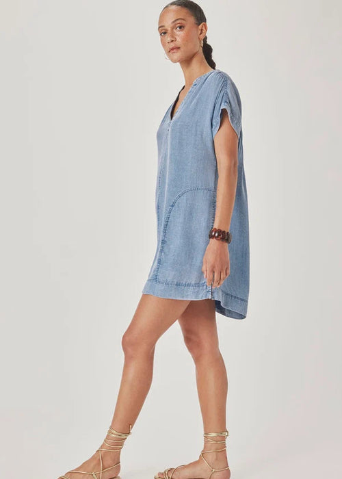 Woman wearing a blue denim dress on a plain background