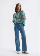 Person wearing a teal sweater and blue jeans on a white background