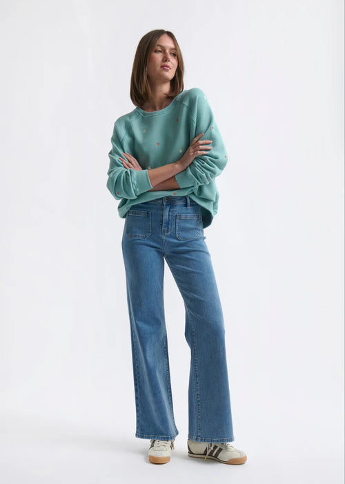 Person wearing a teal sweater and blue jeans on a white background
