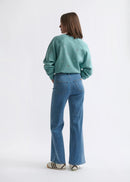 Person wearing a teal sweatshirt and blue jeans on a white background