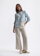 Woman wearing a light blue shirt and beige pants on a white background